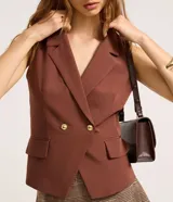 Chaleco marrón de corte sastre con cuello blazer, doble botonadura dorada y bolsillos simulados. Fabricado con procesos más sustentables.