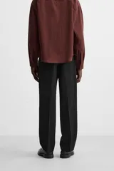 Pantalón negro de corte recto confeccionado en tejido fluido con mezcla de viscosa, con bolsillos frontales y traseros de vivo.