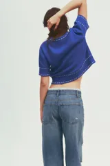 Top azul de tejido de punto con cuello redondo y manga corta. Detalle de pespuntes blancos a contraste en cuello, mangas y ruedo.