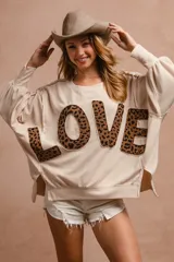 Remerón color crema con mangas largas abullonadas y aplique de letras con estampado animal print formando la palabra "LOVE".