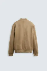 Cazadora bomber negra de corte regular, confeccionada en tejido con efecto ante. Cuenta con cuello, puños y bajo de rib elástico, bolsillos de vivo en la cadera y cierre frontal con cremallera.