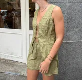 Conjunto de top y falda verde oliva con textura. El top es sin mangas, con escote en V y lazo ajustable en el centro. La falda es corta y ajustada.