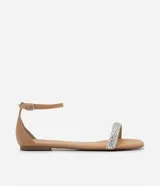 Sandalia plana color nude con tira fina con aplicación de strass y mini espejos, cierre en el tobillo, puntera redonda y taco bajo plano.