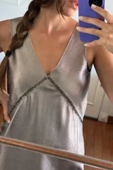 Vestido corto color plateado, con escote en V y espalda descubierta.