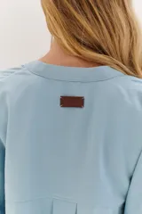 Sobrecamisa celeste de corte recto, con cuello mao, mangas 3/4 con puños y cierre frontal con botones. Tiene dos bolsillos de parche en el pecho.