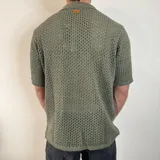 Camisa tejida de manga corta color verde oliva, con cuello tipo polo y cierre frontal con botones.