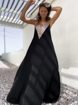 Vestido largo negro con escote en V y apliques de lentejuelas doradas en el corpiño.