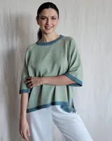 Sweater tejido de punto color verde claro con cuello, puños y ruedo en azul.