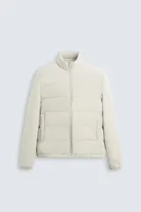 Campera acolchada color beige con cuello alto, cierre frontal con cremallera, bolsillos laterales y puños elásticos.