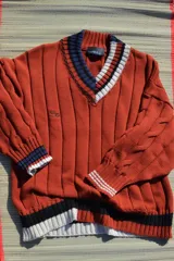 Buzo tejido verde con escote en V, cuello con rayas blancas y azul marino, y puños y ruedo con detalle de rayas.