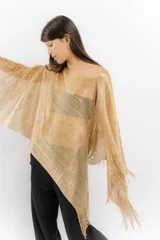Poncho tejido color dorado con apliques de piedras y flecos.