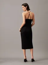 Vestido midi negro de punto canalé crepé con tirantes finos, espalda cruzada con detalle metálico y recorte en la parte delantera de la cintura.
