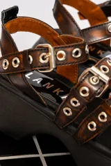 Sandalias de cuero color marrón con plataforma negra y hebillas metálicas.