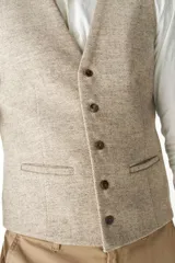 Chaleco de vestir para hombre, color marrón claro con textura tweed. Diseño sastrero con cuello en V, cierre frontal con botones, bolsillos ribeteados y forro interno. Confeccionado en lana fina sin teñir, diseñado exclusivamente por Don Baez.