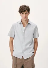 Camisa celeste de manga corta con estampado a cuadros pequeños, cuello clásico y bolsillo en el pecho.