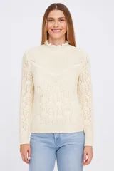 Sweater color crudo con cuello alto con volados y tejido calado.