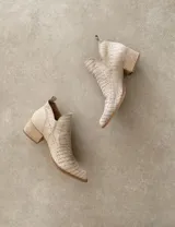 Botín de cuero color marrón claro, con punta fina, cierre lateral con cremallera dorada, detalle de pespuntes en el empeine y taco cuadrado de madera color negro.