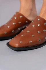 Zueco marrón de cuero con tachas plateadas.