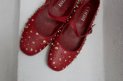 Chatas negras de cuero con correa sobre el empeine y hebilla plateada. Decoradas con tachas plateadas y doradas de diferentes tamaños.