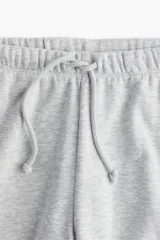 Jogger gris melange en felpa con cintura elástica y cordón para ajustar. Modelo de corte holgado con bolsillos discretos en las costuras laterales y piernas amplias.