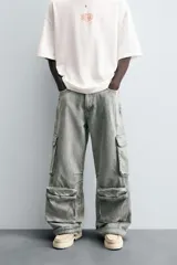 Pantalón relaxed fit de denim negro con efecto lavado, bolsillos frontales, traseros de plastrón y multifunción en perneras. Bajo ajustable con trabilla y cierre frontal con cremallera y botón.