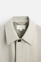 Gabardina color beige de corte relaxed fit, confeccionada en tejido italiano repelente al agua. Tiene cuello solapa, manga larga con puños abotonados, bolsillos de vivo en la cadera, bolsillo interior y abertura en la espalda.