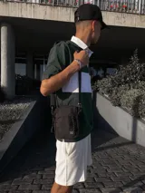 Bandolera negra con correa ajustable y cinco bolsillos.