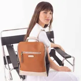 Mochila combinada en tres tonos: marrón, beige y negro. Tiene un bolsillo frontal con cierre, asa de mano y correas regulables.