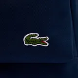 Mochila azul marino de poliéster con compartimento principal con cierre, bolsillo frontal con cierre y logo de Lacoste bordado en verde.