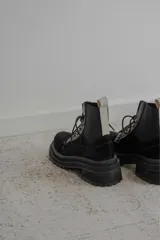 Borcego de gamuza color verde militar con elásticos laterales negros, cordones negros y suela de goma negra con plataforma.