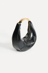 Bolso negro de formato ovalado con asa metálica dorada. Tiene detalle de pespunte en contraste en el cuerpo, bolsillo interior con cremallera y cierre mediante cremallera y tirador.