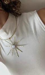 Collar artesanal con dije en forma de sol con centro de nácar triangular y rayos de metal dorado texturizado. Incluye cordón de gamuza ajustable.
