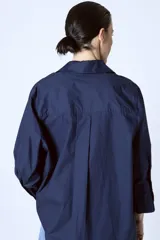 Camisa azul marino de corte holgado, con cuello clásico, cierre frontal con botones y mangas 3/4.