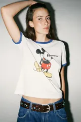 Camiseta blanca de algodón con cuello redondo y mangas cortas con ribete azul. Estampado frontal de Mickey Mouse y texto 'California'.
