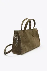 Bolso tipo city bag color verde oliva, confeccionado en cuero serraje. Tiene doble asa de mano trenzada y asa bandolera extraíble. Incluye detalles metálicos laterales y bolsillo interior con cremallera.