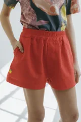 Short rojo de algodón y lino con cintura elástica, bolsillos laterales y bordado de un limón en la pierna izquierda.