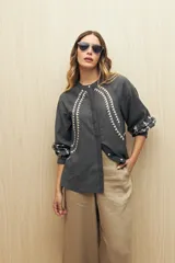 Camisa gris oscuro con estampado de triángulos blancos en el frente, mangas y cuello.