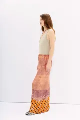Pantalón amplio de viscosa y modal con cintura elastizada. Presenta un estampado batik en tonos naranja, terracota y morado, con textura plisada y apliques de lentejuelas circulares plateadas.
