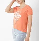 Remera color salmón de corte crop, con cuello redondo y mangas cortas con dobladillo. Estampado frontal con texto en blanco.
