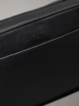 Bolso bandolera negro de Calvin Klein, confeccionado en piel sintética suave. Tiene correa ancha ajustable, cierre de cremallera, bolsillo exterior y bolsillo interior.