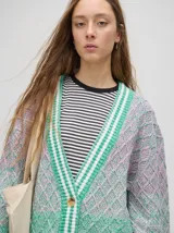 Cardigan tejido de punto con patrón de rombos en degradé de grises y blanco. Tiene corte oversize, mangas largas y cierre frontal con botones.