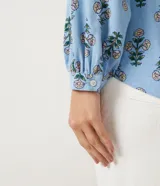 Camisa celeste de viscolino con estampado floral, cuello camisero y mangas largas.