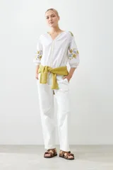 Blusa blanca de estilo boho con bordados de flores en amarillo y azul en mangas y escote.