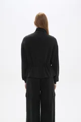 Campera negra de poliéster con cierre frontal, cuello alto, bolsillos con solapa en el pecho y cintura ajustable con cordón.