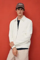 Campera blanca de denim rígido con cuello clásico, cierre frontal con cremallera, bolsillos laterales y un bolsillo interior. Tiene elástico en puños y bajo. Corte estándar y forro interior.