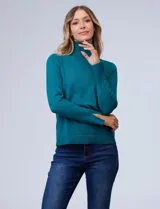 Polera de punto fino marca Nienty, color blanco, con cuello alto volcado y mangas largas con detalle de tajo en los puños.