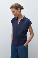 Remera de manga corta color rosa pálido, con cuello polo y escote en V con detalle de bordado en el borde.