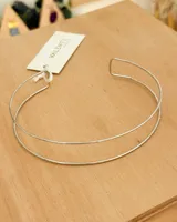 Choker de metal plateado, estilo abierto, compuesto por dos aros finos y paralelos que se unen en la parte posterior. Presenta un diseño minimalista y moderno.