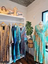 Kimono largo de seda con estampado floral en tonos verde, marrón y beige. Tiene mangas amplias y corte cruzado con lazo ajustable en la cintura.