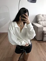 Buzo blanco de tejido de punto con cuello polo y mangas largas.